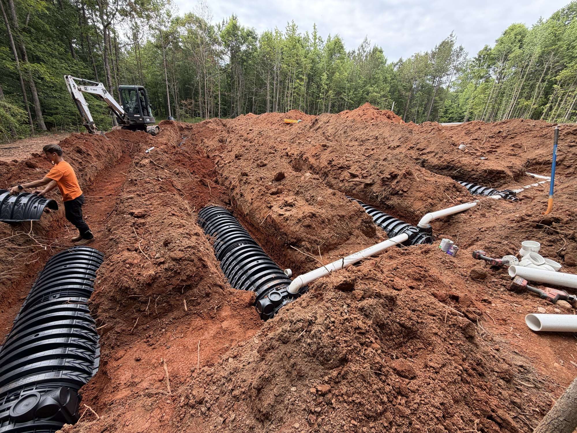 Crew setting drain field chambers with the excavator behind