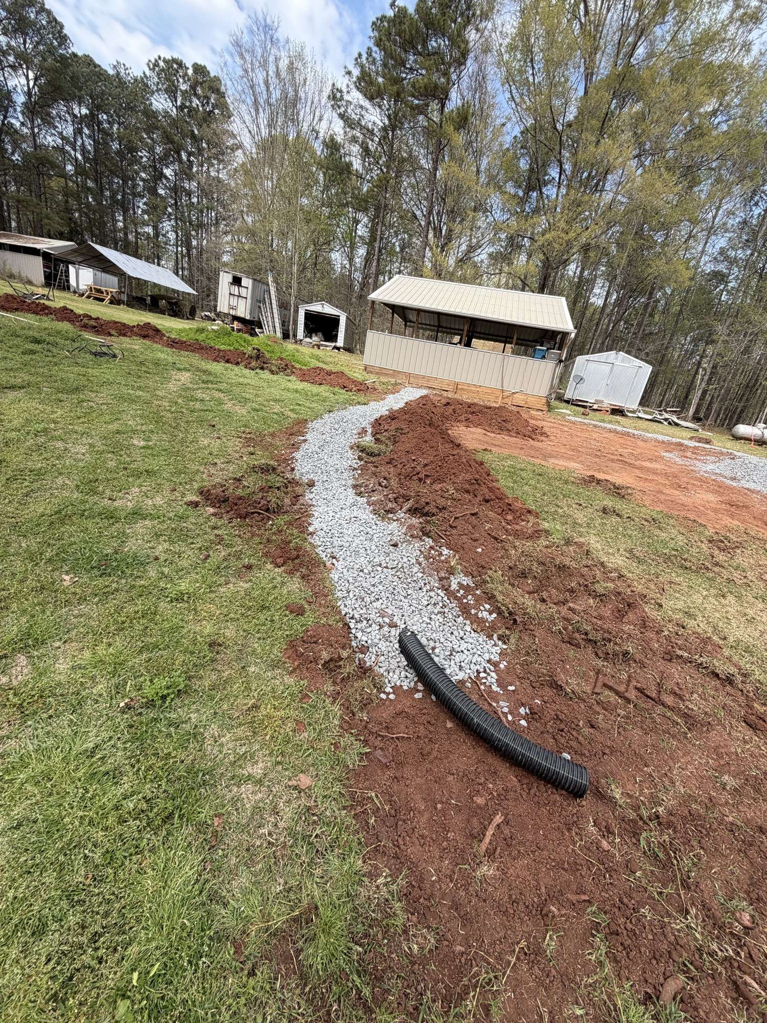 Gravel drain line repair running across a lawn